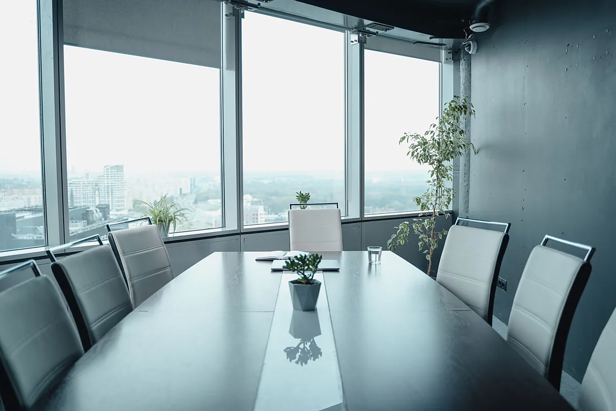 Sala de reunião com mesa longa e janelas amplas com vista da cidade